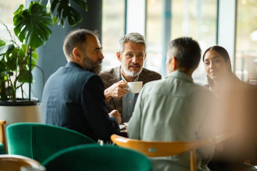 Mature business colleagues discussing over coffee in a modern cafe